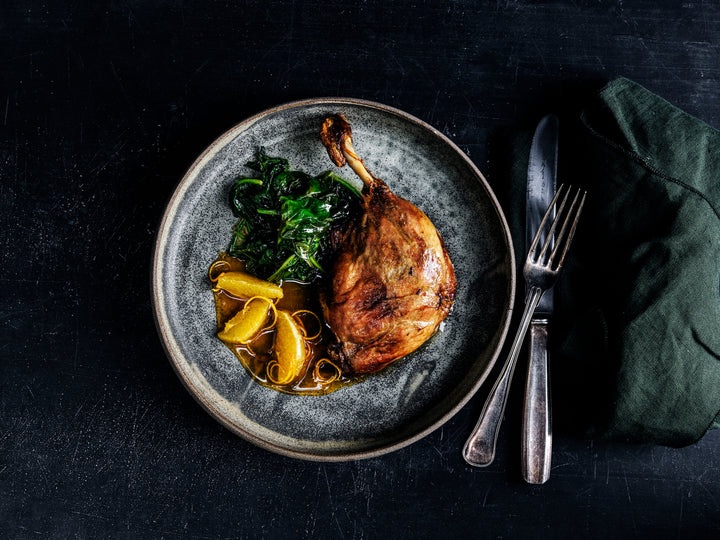 Duck confit with sautéed spinach and orange sauce